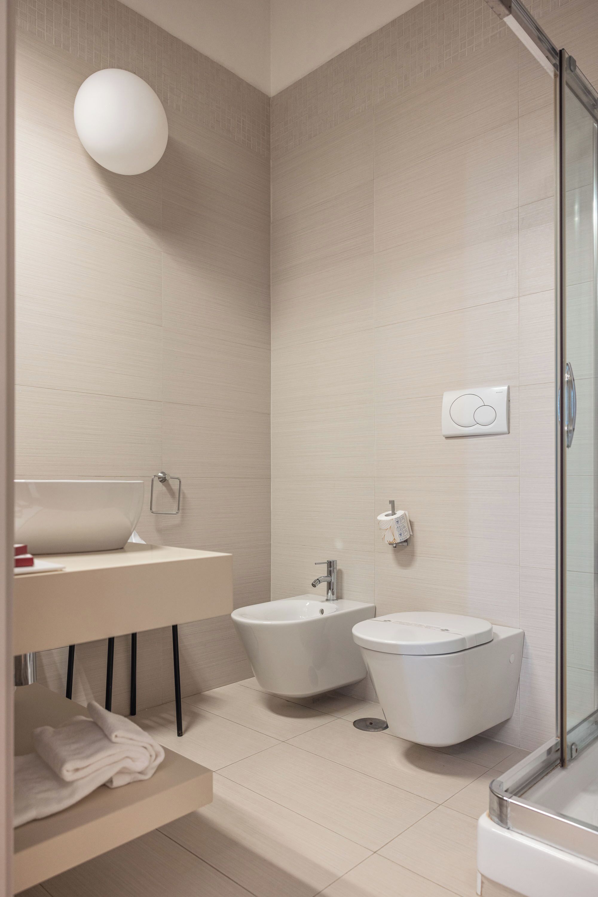 Een moderne badkamer met een wastafel, toilet, douchecabine en een bidet.