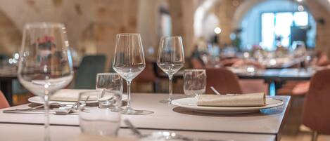 A restaurant setting with tables set for dining, featuring wine glasses, plates, and cutlery.