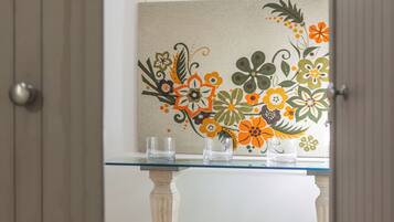 A hallway with a glass-top table, a decorative floral wall, and a tiled floor.