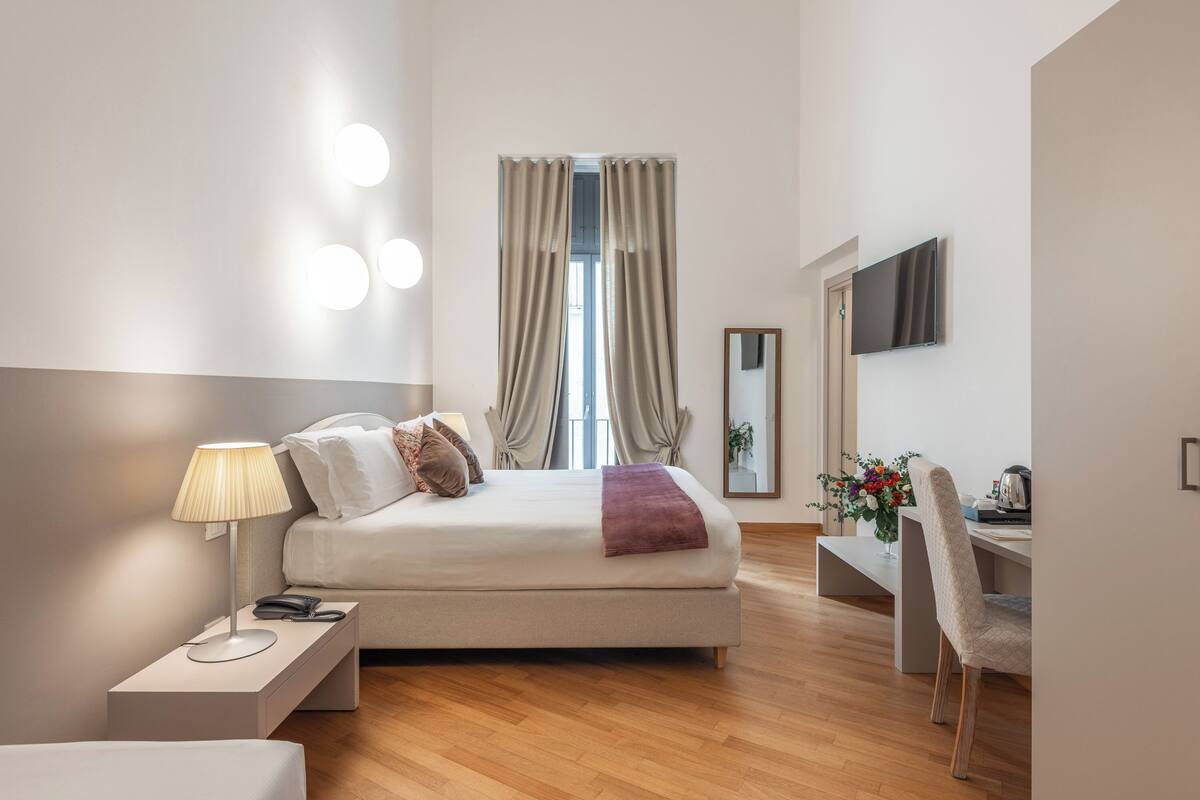 Un dormitorio moderno con cama, mesita de noche, lámpara y escritorio con silla.