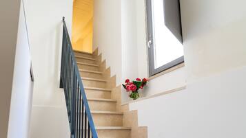 A staircase with beige steps and a black railing, leading to a room with a window and a door.