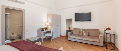 Une chambre d’hôtel moderne équipée d’un lit, d’un bureau, d’un canapé, d’une télévision et d’une salle de bain.