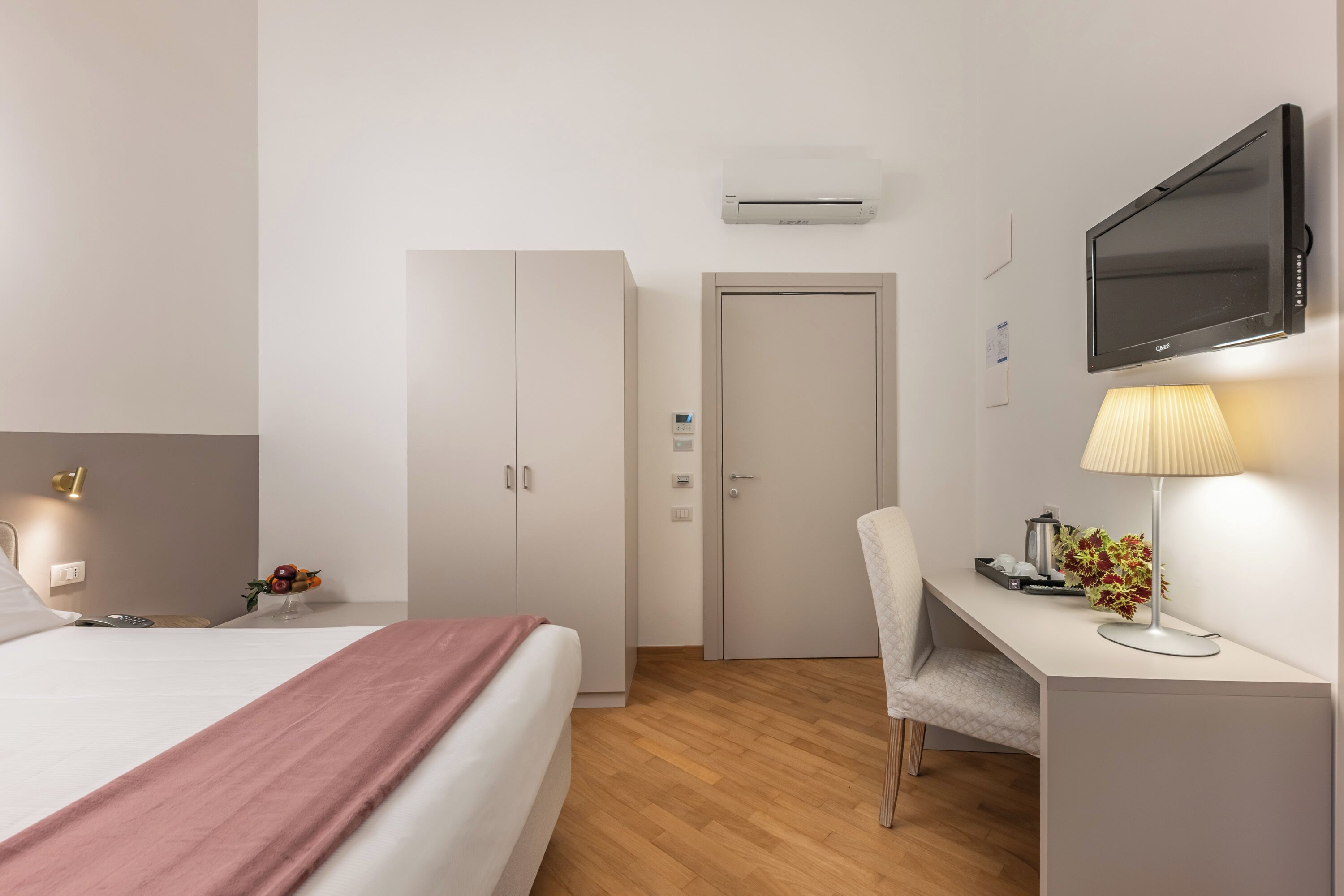 Une chambre d’hôtel équipée d’un lit, d’un bureau, d’une chaise, d’une télévision, d’un climatiseur et d’une lampe.