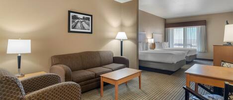 Una habitación de hotel con sofá, una mesita, cama, escritorio y lámpara.