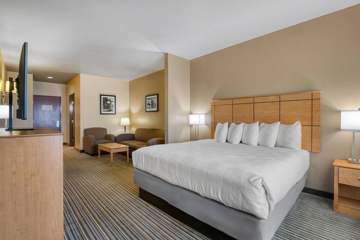 Ein Hotelzimmer mit einem großen Bett, einem Schreibtisch, einem Stuhl und zwei Lampen.