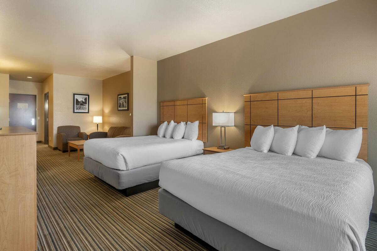 Ein Hotelzimmer mit zwei Betten, einem Schreibtisch, einem Stuhl und einer Lampe.