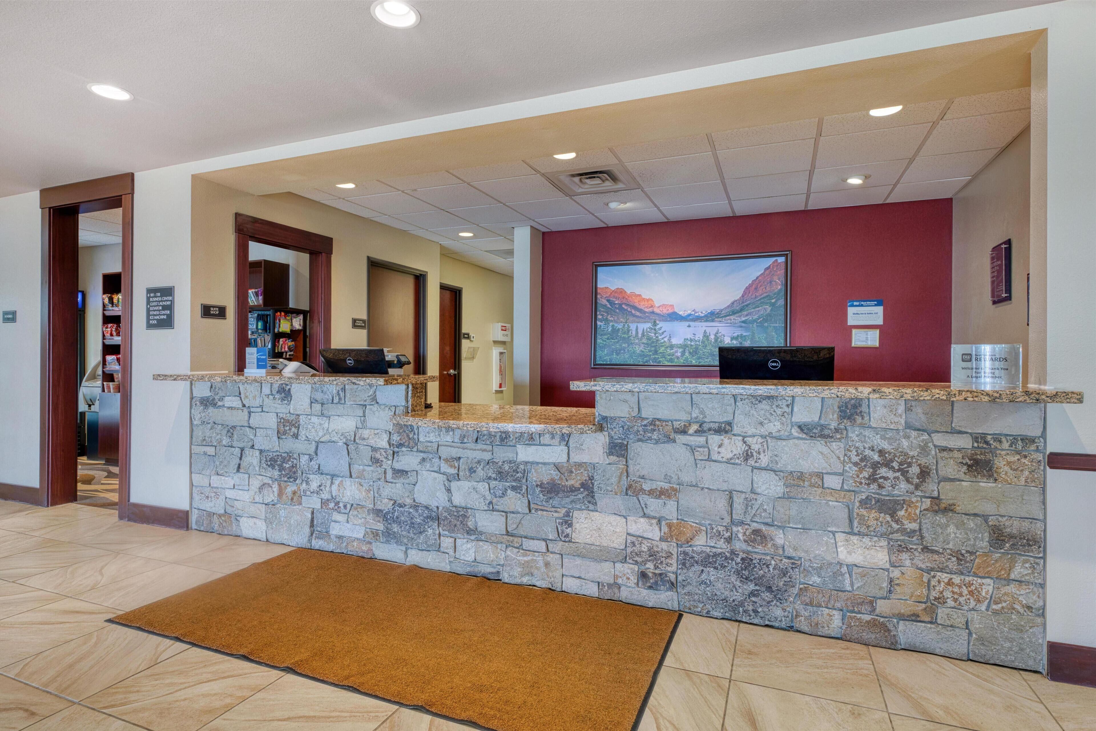 A reception area with a stone counter, a large screen displaying a scenic image, and a sign indicating a business center.