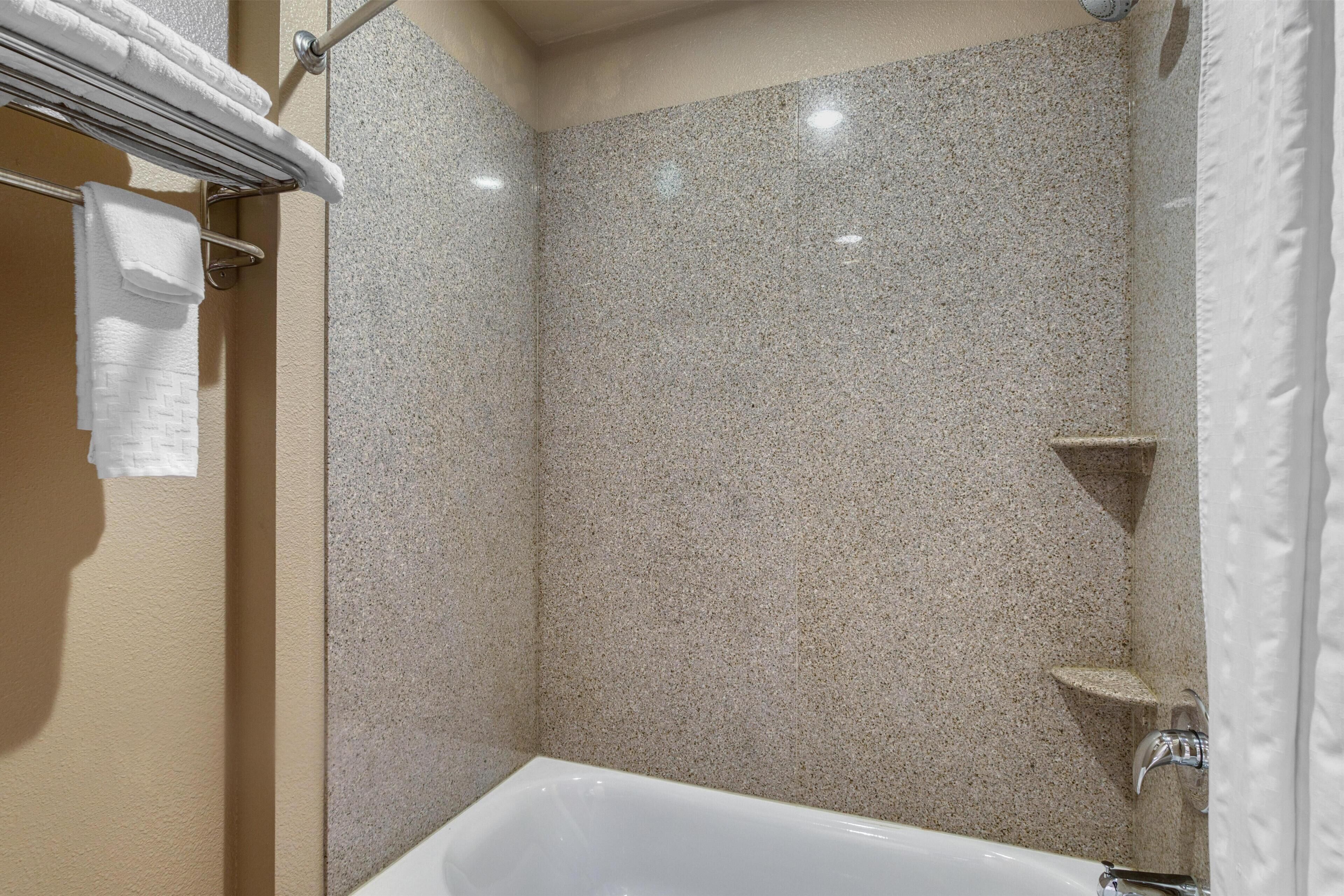A bathroom with a bathtub, a towel rack, and a shower area.