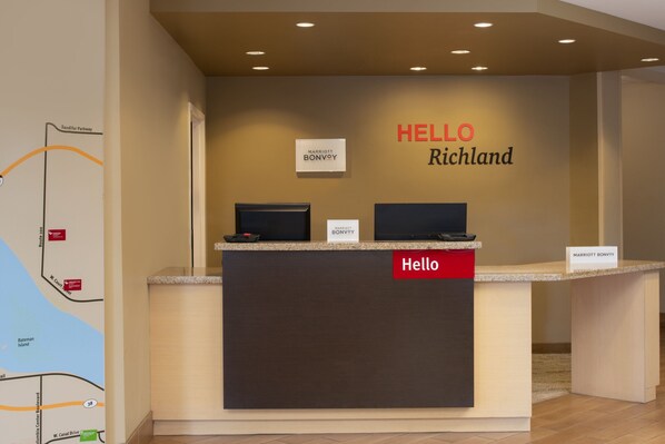 A reception desk with a 'Hello' sign, two monitors, and 'Marriott Bonvoy' signage.