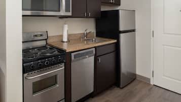 A kitchen with a stove, microwave, dishwasher, and refrigerator.
