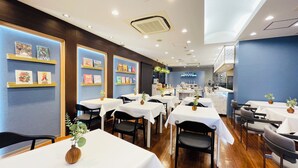 Un restaurant amb diverses taules, cadires i una zona de cuina al fons.
