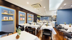 A restaurant with multiple tables, chairs, and a kitchen area in the background.