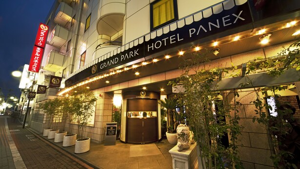 Exterior de l'Hotel Grand Park Panex, amb una entrada ben il·luminada, plantes en testos i una vista clara de les portes d'entrada.