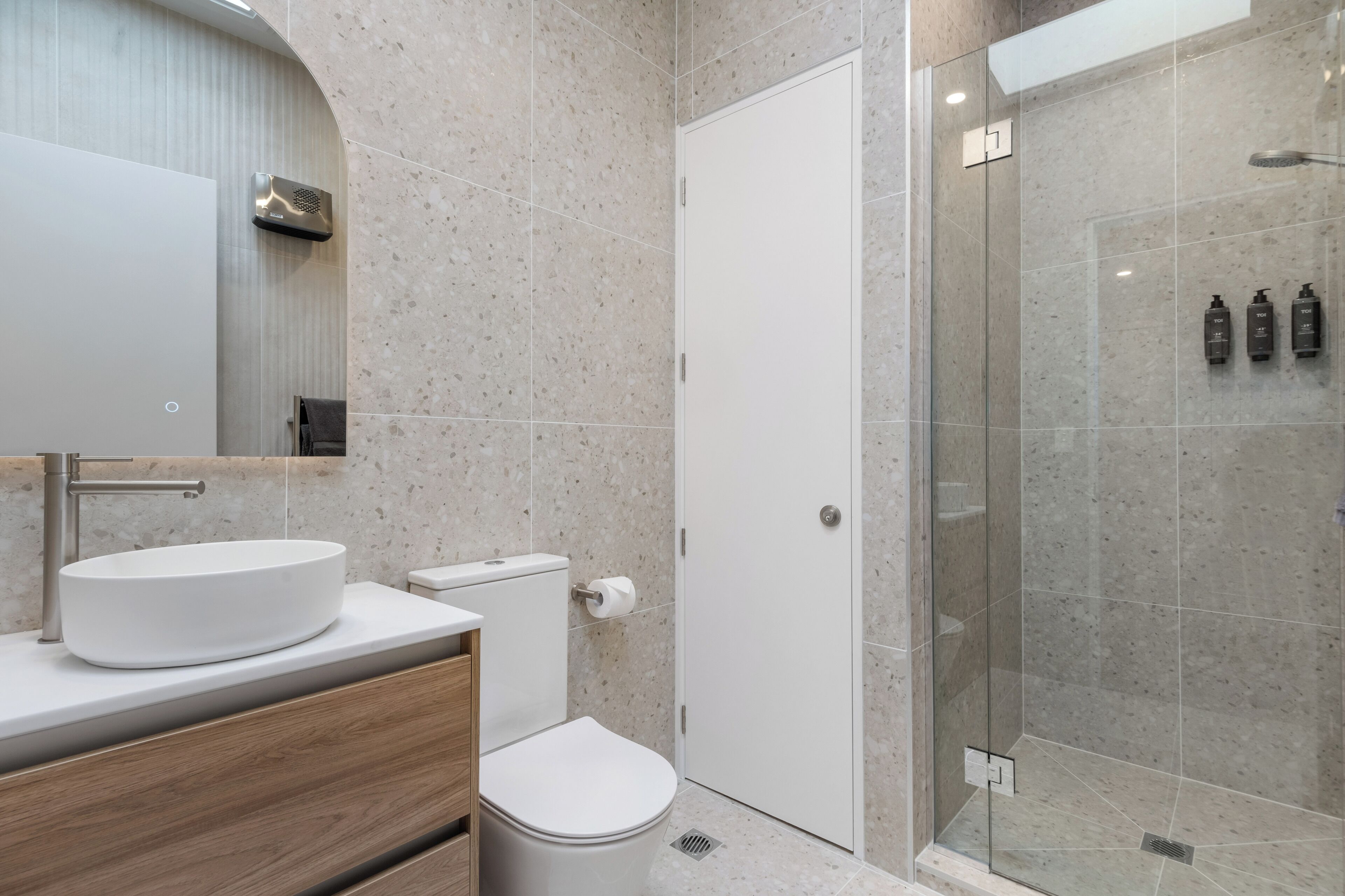 Une salle de bain moderne avec un lavabo sur pied, des toilettes et une douche à parois de verre.