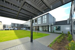 Een modern gebouw met een overdekt buitengebied, een gazon en een parkeerplaats.