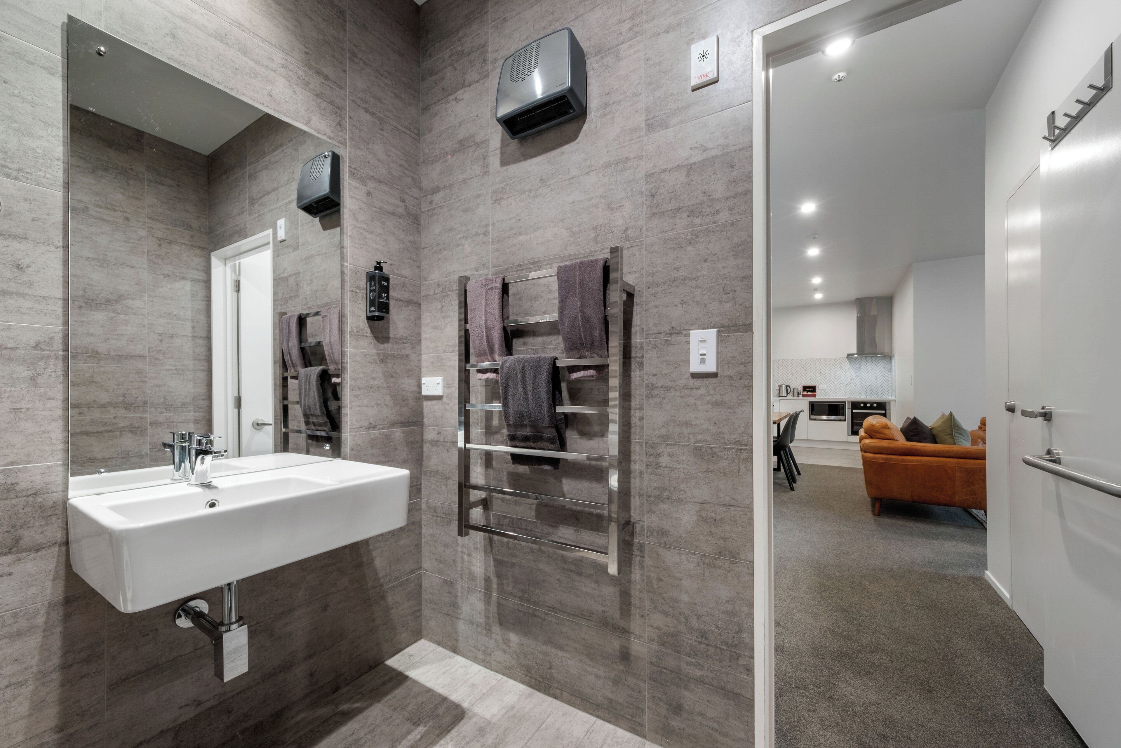 A modern bathroom with a large sink, towel rack, and a mirror.