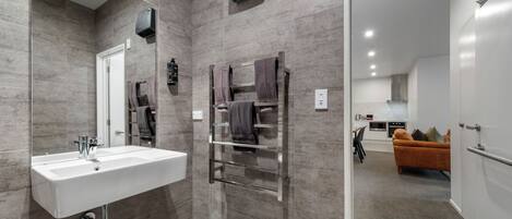 A modern bathroom with a large sink, towel rack, and a mirror.
