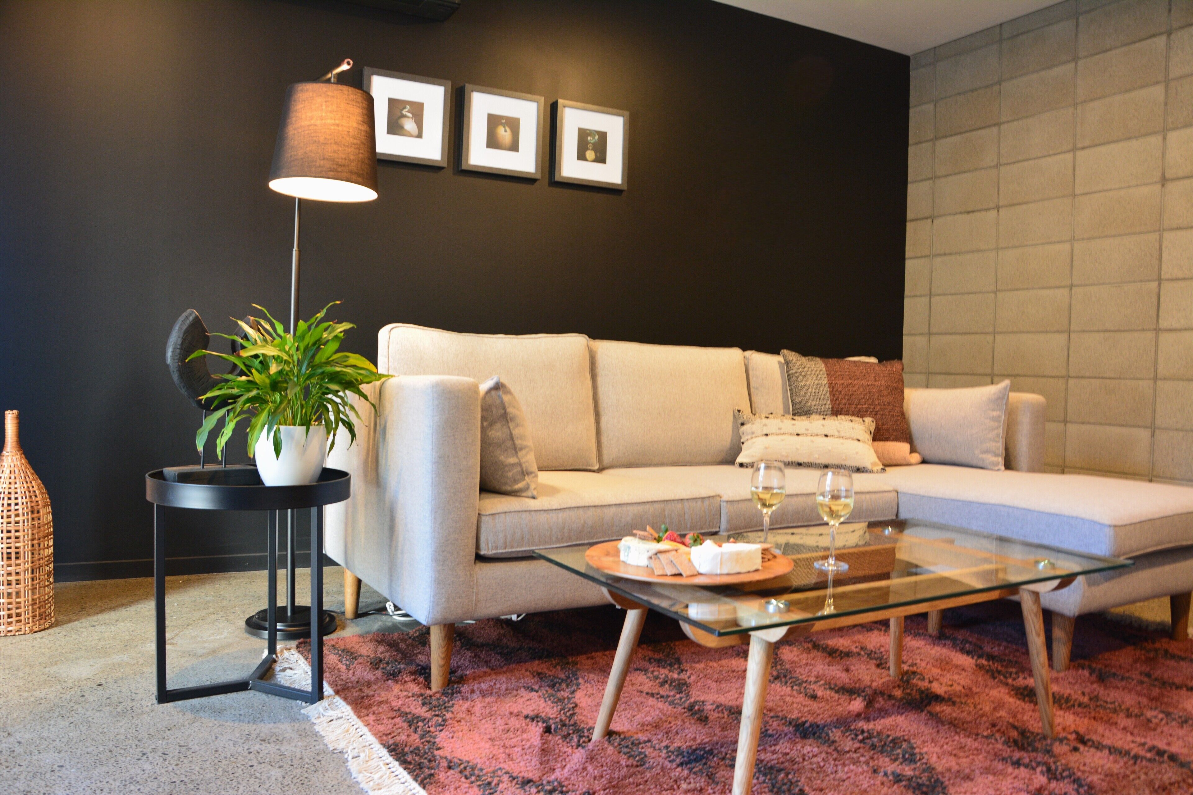 Een moderne woonkamer met een bank, een glazen salontafel, een potplant en een lamp.