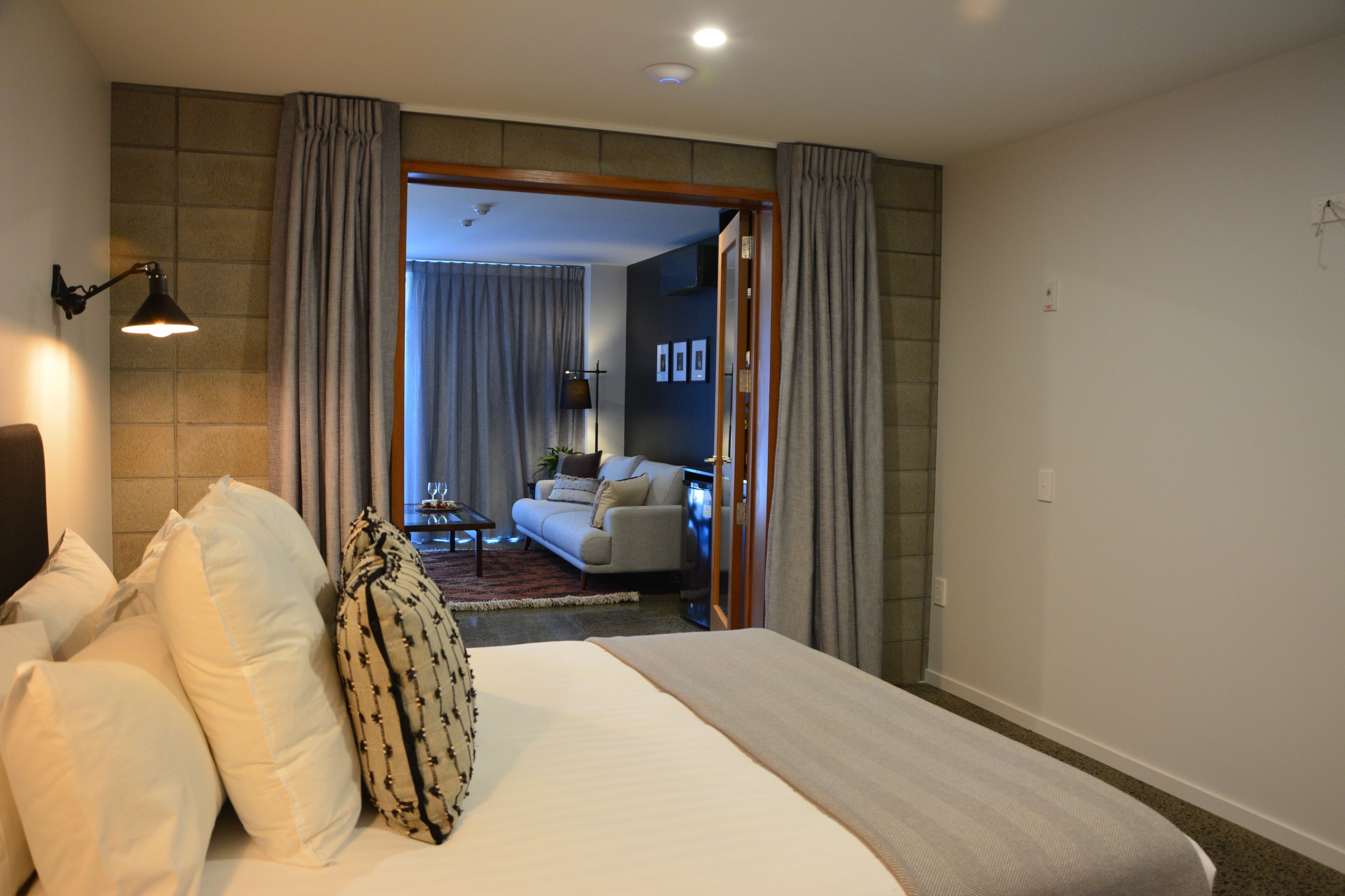 Une chambre d’hôtel avec un grand lit, un bureau et une vue sur un espace de vie comprenant un canapé et un téléviseur.