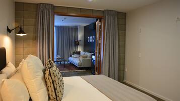 Hotelkamer met een groot bed, een bureau en uitzicht op een zithoek met een bank en een televisie.