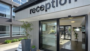 Un área de recepción con diseño moderno, que incluye una puerta de cristal y un cartel sobre ella.