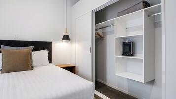 Un dormitorio ordenado con cama, mesita de noche y vestidor con estantes.