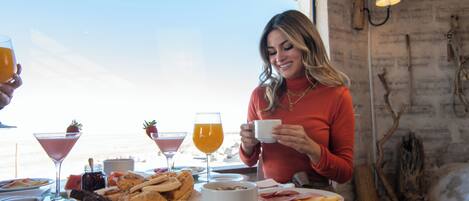 A breakfast table with various dishes, a drink, and a person holding a cup.