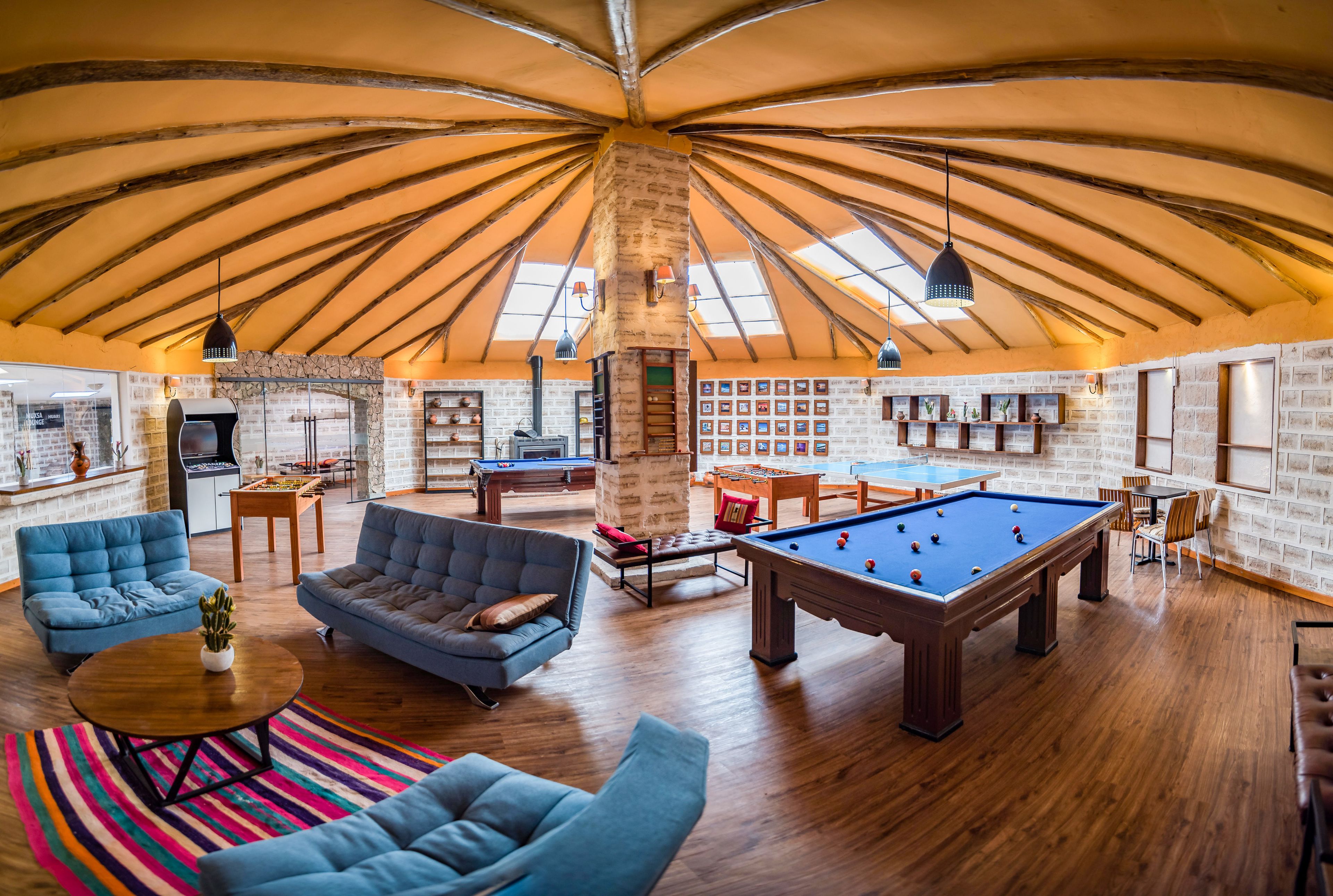 Un grand espace intérieur comprenant une table de billard, des canapés et une table de jeu de flipper.