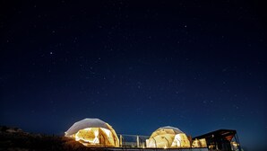 Two dome-shaped structures with illuminated interiors, set against a starry night sky.