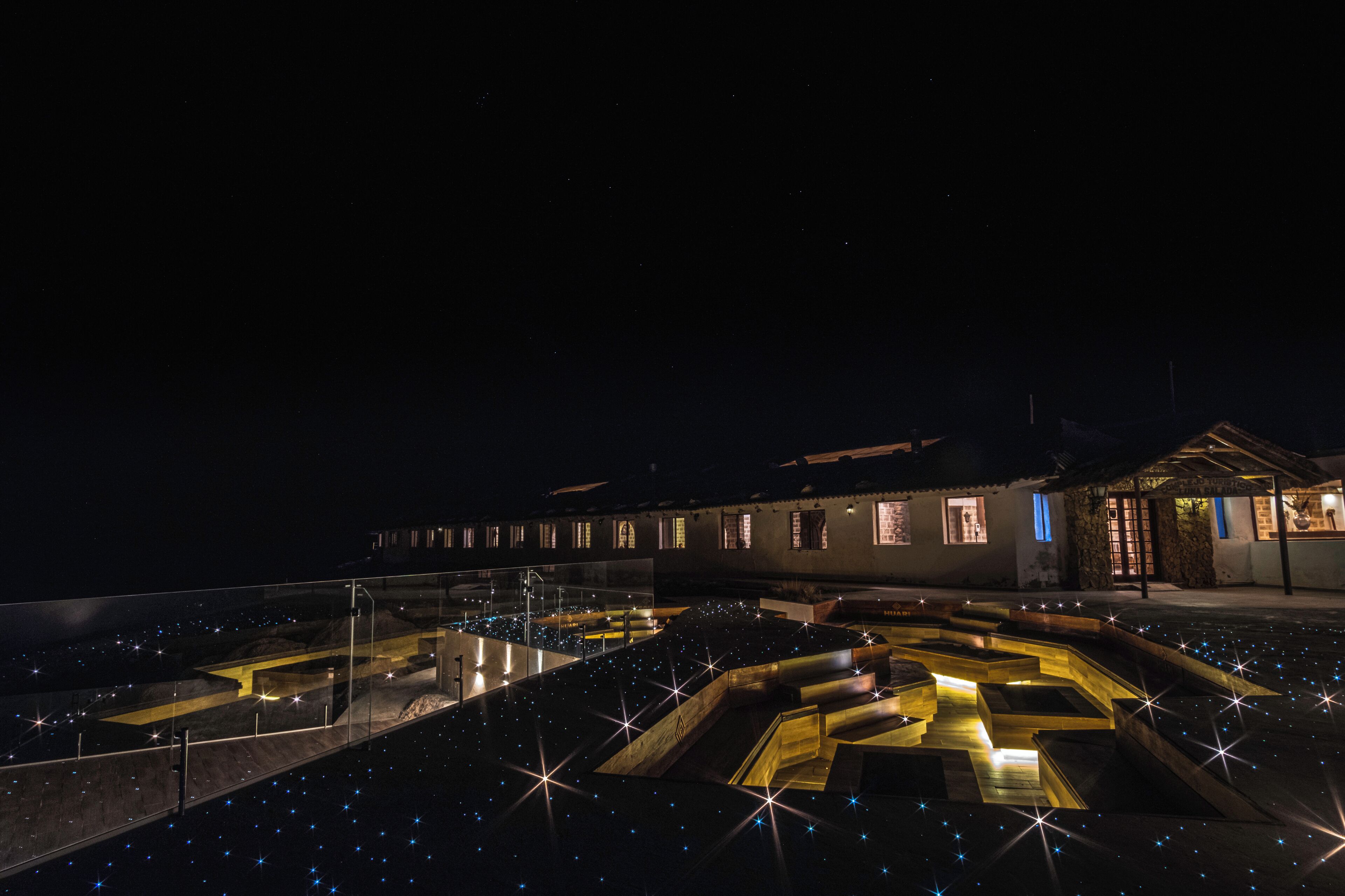 Vista nocturna de un edificio con un patio que presenta diseños geométricos y luces similares a estrellas.
