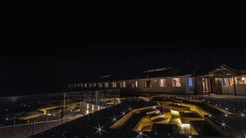 Vista nocturna de un edificio con un patio que presenta diseños geométricos y luces similares a estrellas.