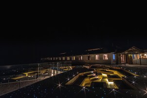 Vista nocturna de un edificio con un patio que presenta diseños geométricos y luces similares a estrellas.