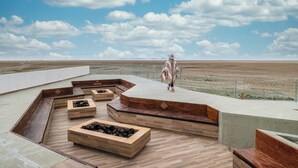 A spacious outdoor terrace with wooden planters and seating areas, offering expansive views of the landscape.