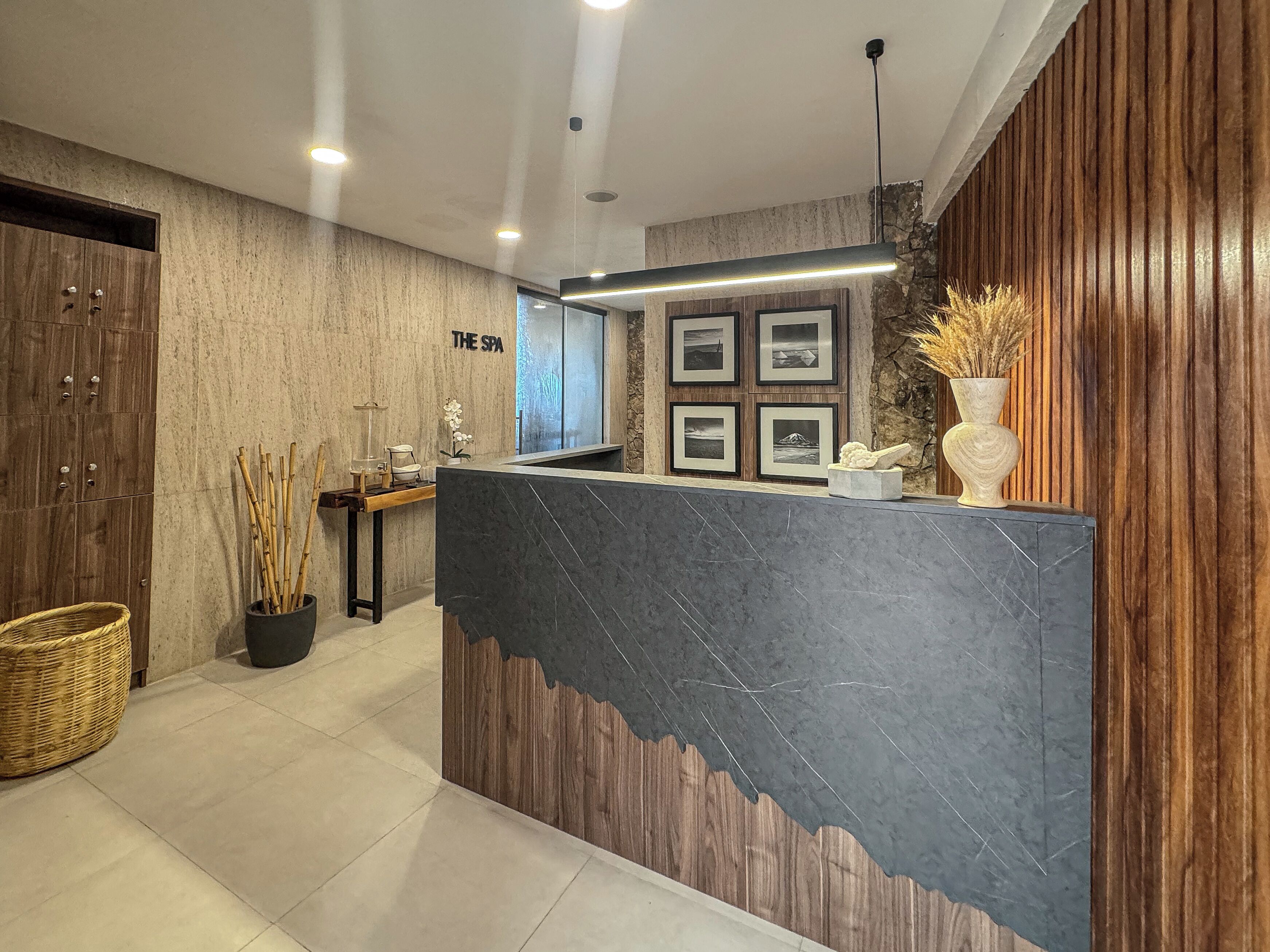 A reception area with a wooden reception desk, a stone wall, and framed pictures on the wall.