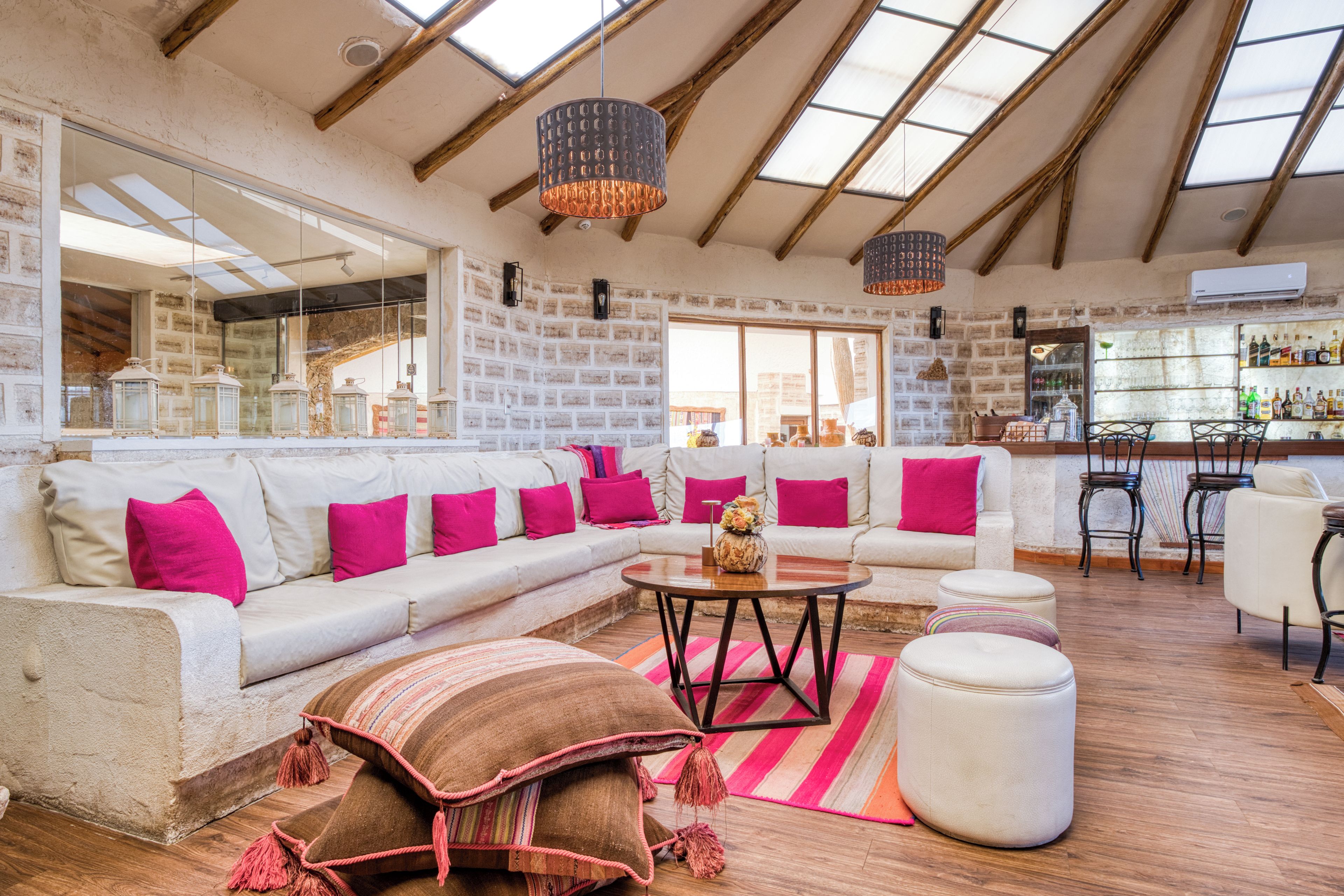 Amplia sala de estar con techo alto, un sofá grande, una mesa de centro y una zona de bar con estantes llenos de botellas.
