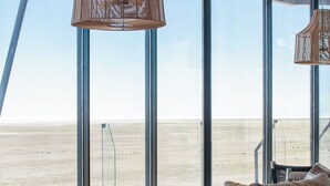 A room with large windows, wicker furniture, and a view of the beach.