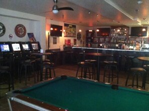 A bar area with pool tables, a bar counter, and various wall decorations. - Airport Lodge (Waukesha)