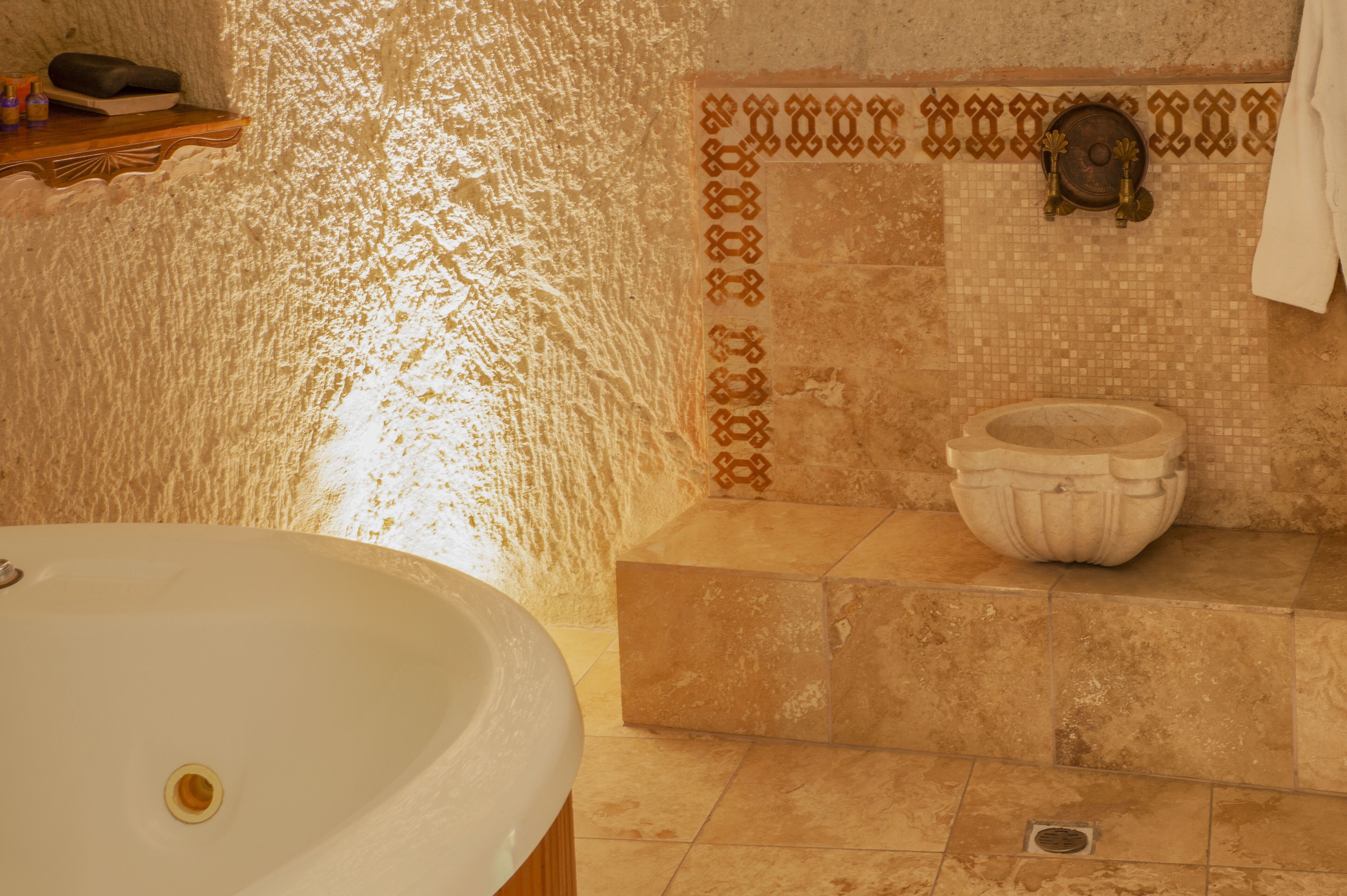 A bathroom with a large bathtub, a shower area, and a decorative wall with a patterned tile border.
