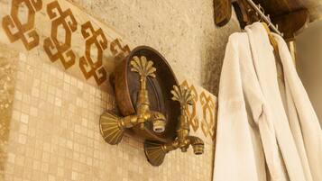A bathroom with a tiled wall, a brass faucet, and a towel rack.