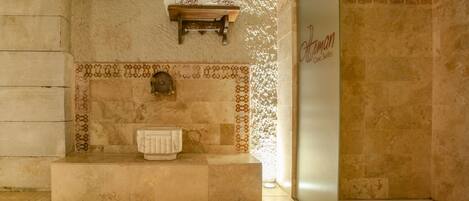 A bathroom with a stone wall, a wooden shelf with towels, and a sign that reads "Atonan Cove Suites."