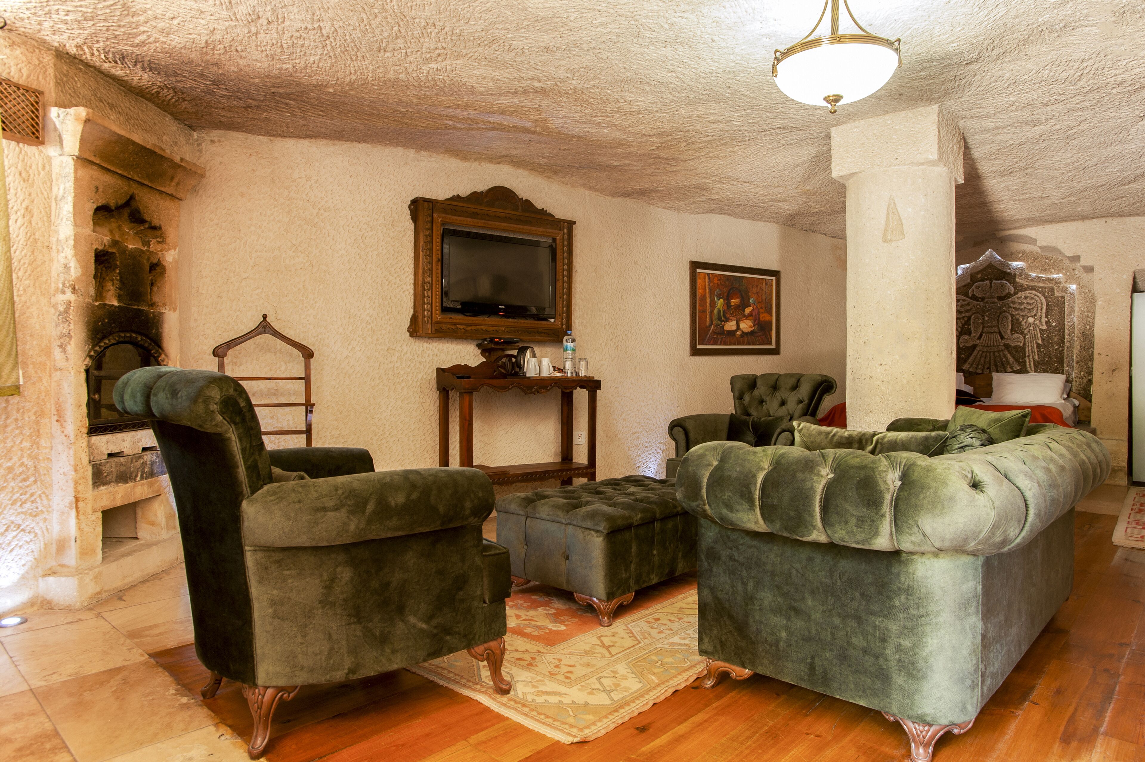 Una sala de estar con un sofá verde, dos sillones, una mesa de centro de madera, un televisor y una chimenea.