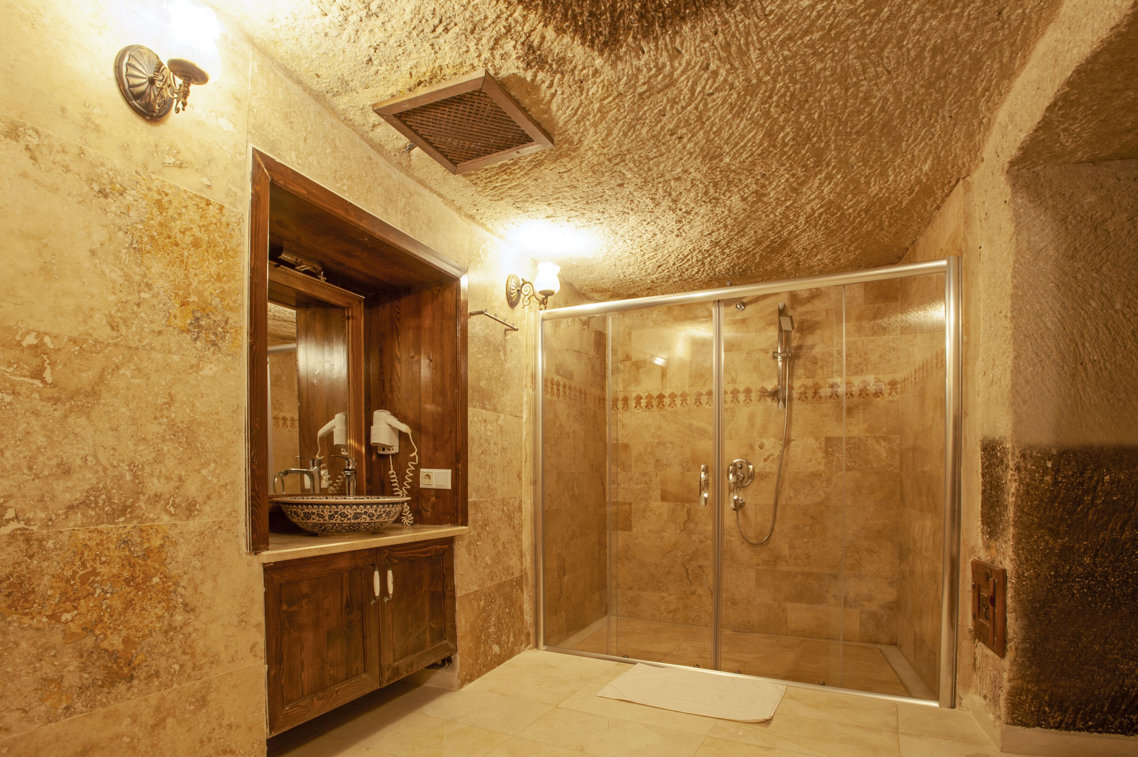 A bathroom with a wooden vanity, a glass-enclosed shower, and a textured ceiling.