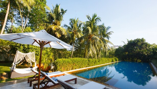 Un espace aménagé au bord de la piscine, avec des chaises longues et un auvent.