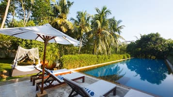 Una piscina al aire libre, sombrillas, sillones reclinables de piscina