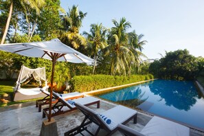 Un espace aménagé au bord de la piscine, avec des chaises longues et un auvent.
