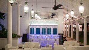 Un espace intérieur bien éclairé, avec des colonnes blanches, des luminaires suspendus et des espaces aménagés pour s’asseoir.