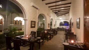 An indoor dining area with multiple tables and chairs, arched ceilings, and a view of the outdoor patio.