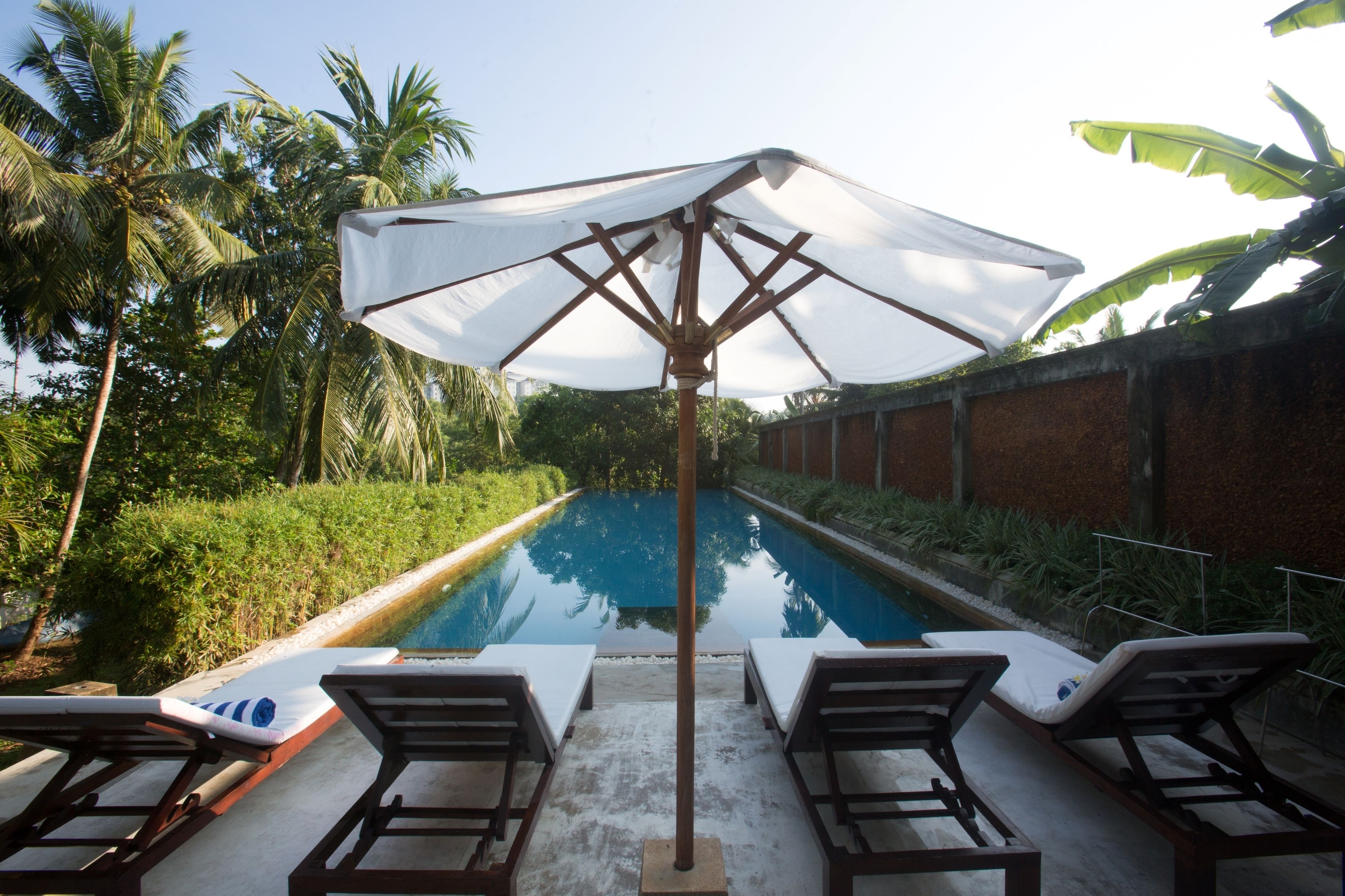 Uma piscina com espreguiçadeiras e um guarda-sol.