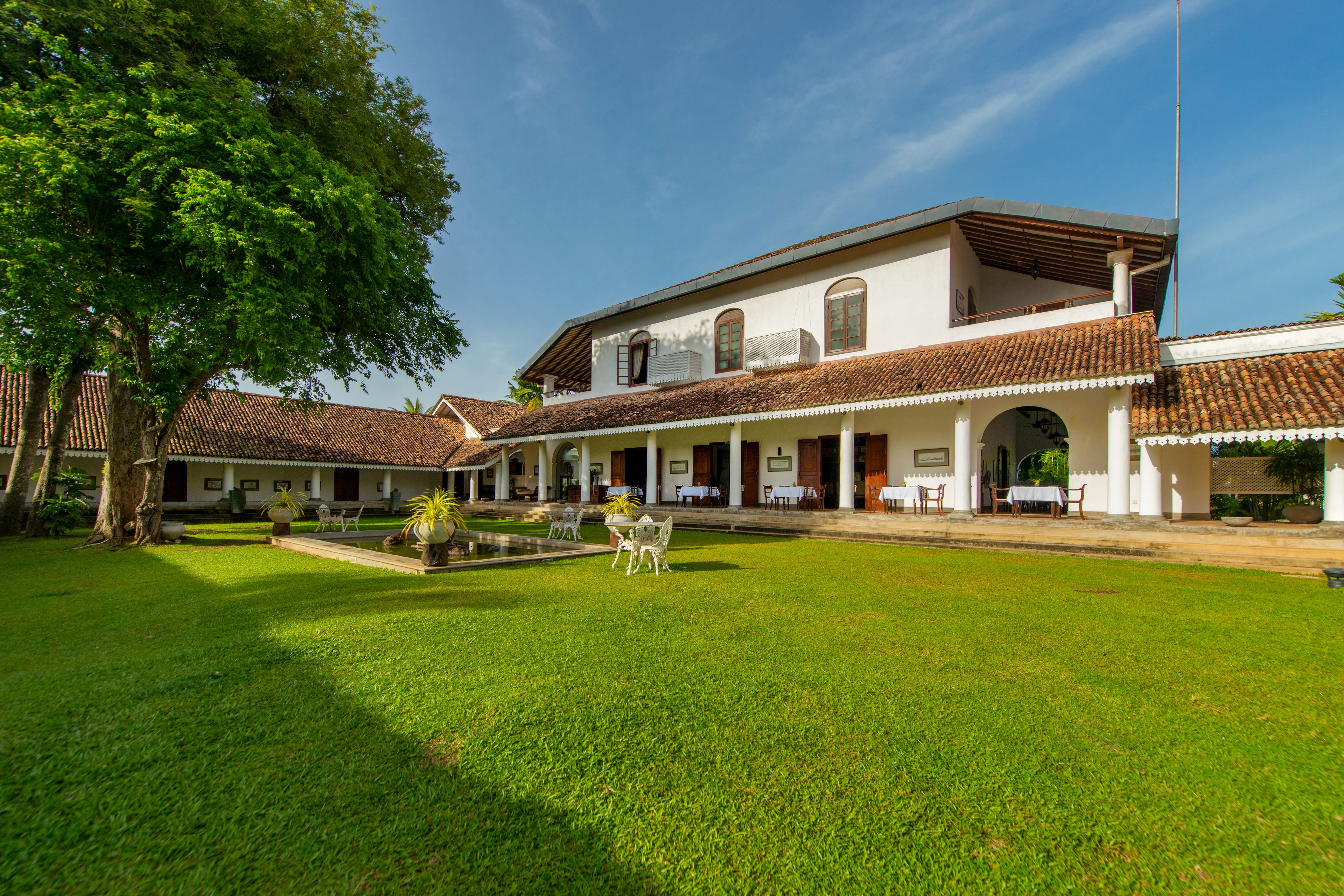 Um edifício em estilo colonial com pátio, colunas brancas e telhado em azulejos.