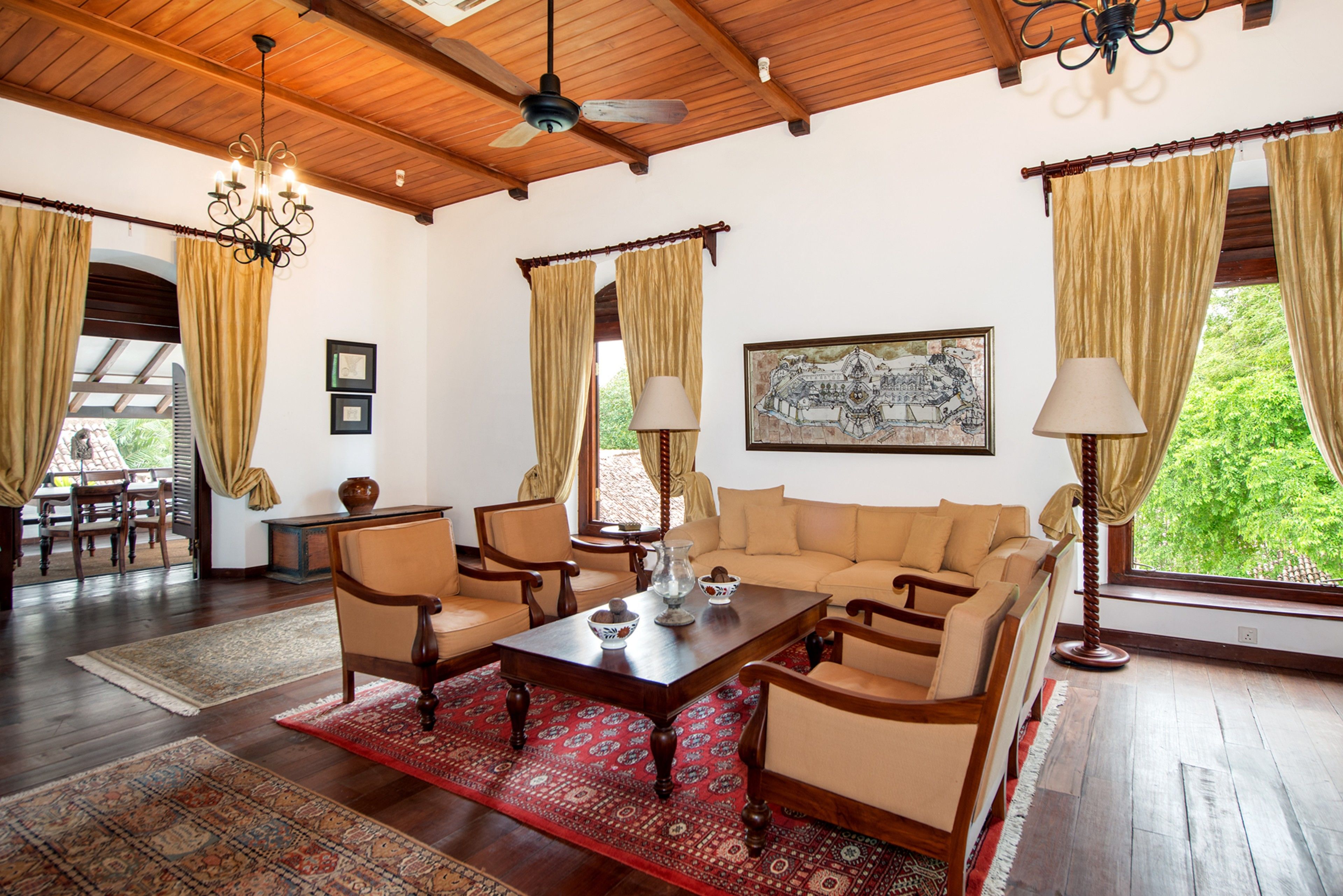 A spacious living room with a wooden ceiling, a large sofa set, a coffee table, and a chandelier.